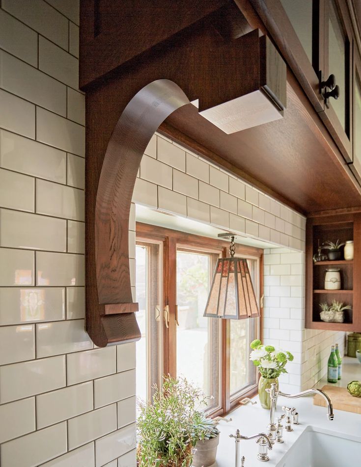 a kitchen sink sitting under a window next to a wooden shelf filled with potted plants