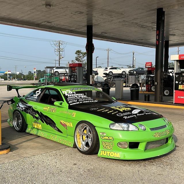 a green car parked in front of a gas station