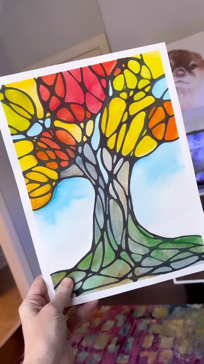 a person holding up a card with a stained glass tree on it