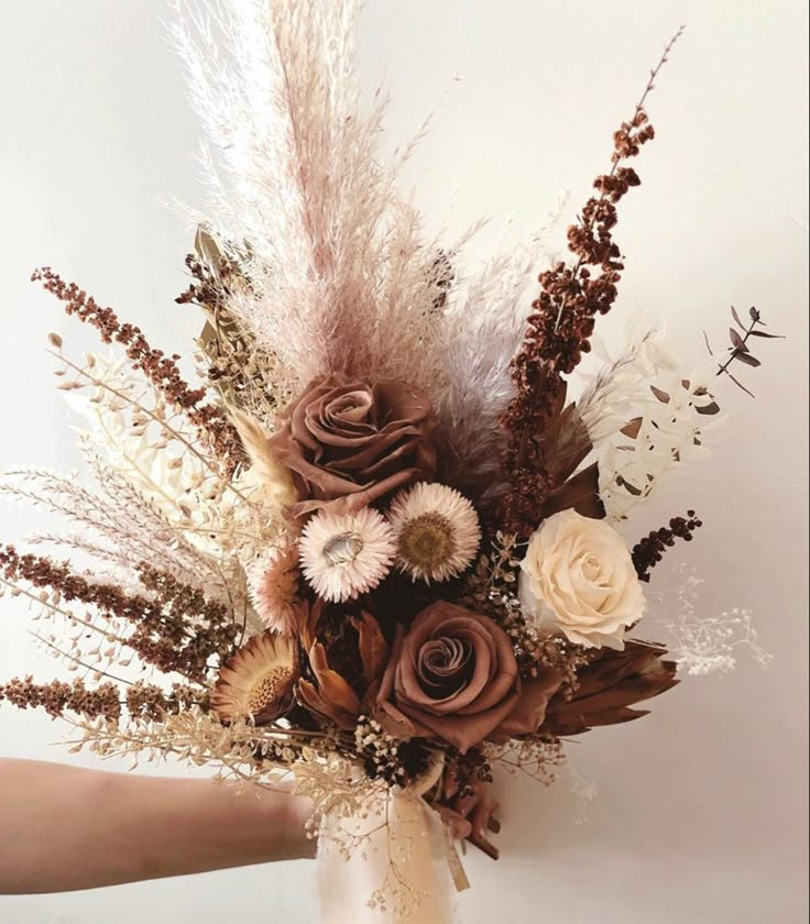 a vase filled with flowers and feathers on top of a table