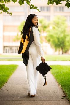 a woman walking down a sidewalk holding a black and yellow book case in her hand