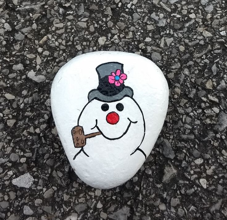 a painted rock with a snowman holding a stick on it's face and wearing a top hat