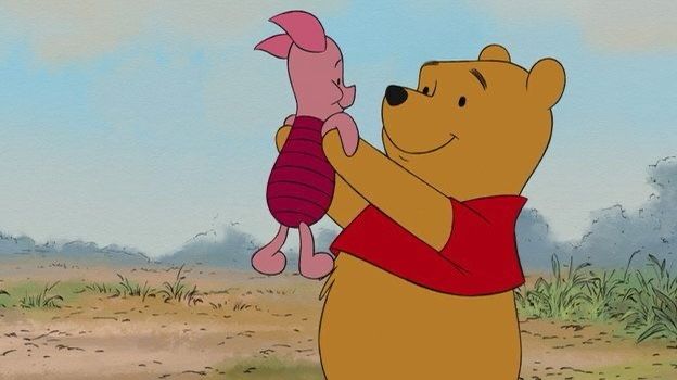 winnie the pooh is holding a pink toy