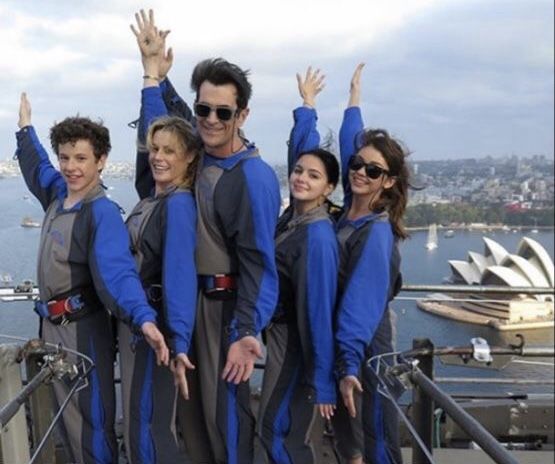 a group of people standing next to each other on top of a metal structure with their hands in the air