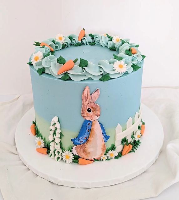 a blue cake decorated with an image of a rabbit on it's side and flowers around the edges