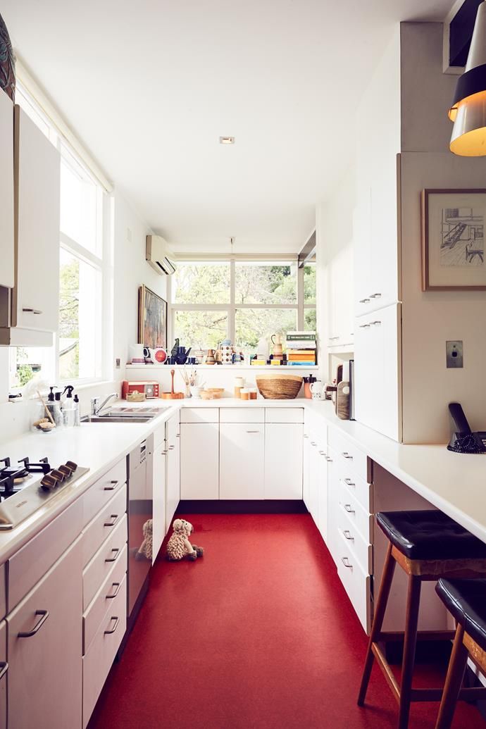 a kitchen with red carpet and white cabinets