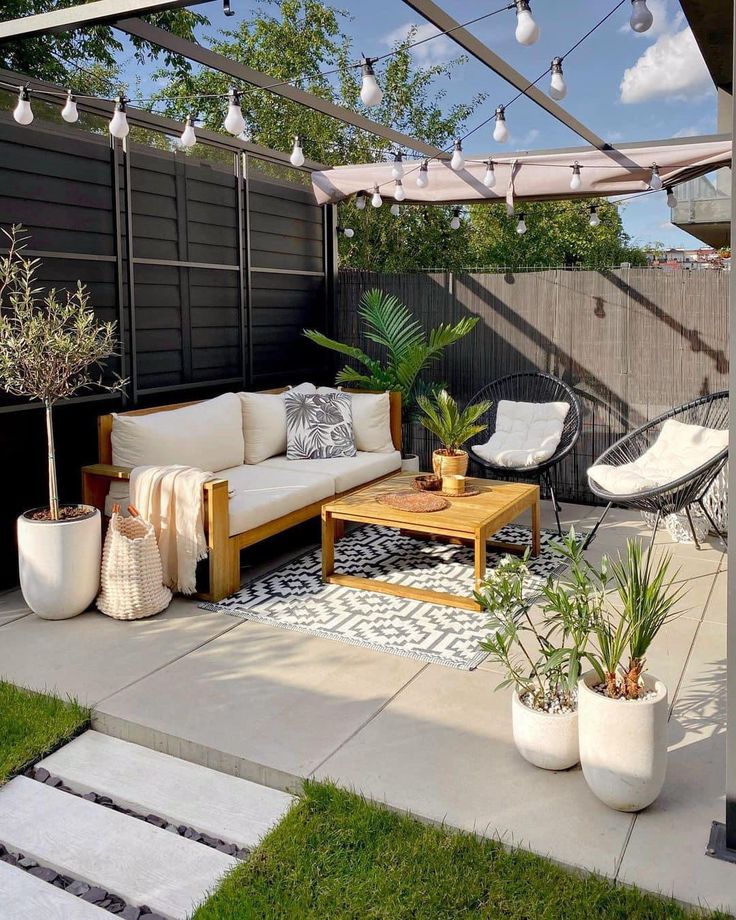 an outdoor living area with white furniture and plants