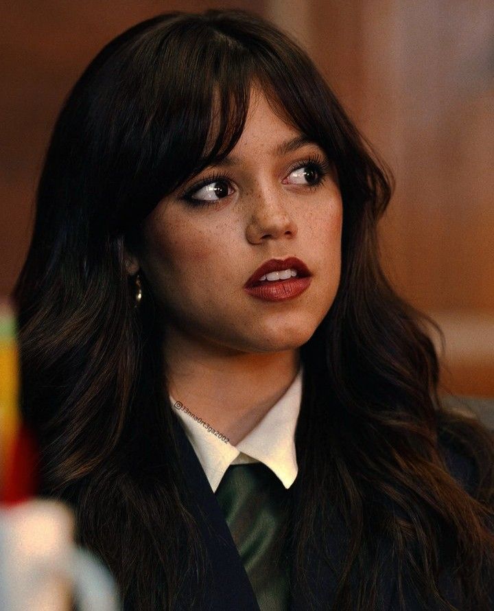 a close up of a person wearing a suit and tie with long dark brown hair