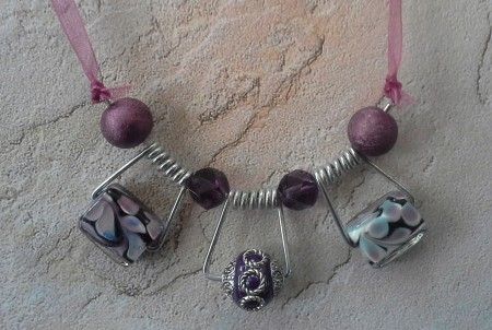 a necklace with purple beads and silver charms