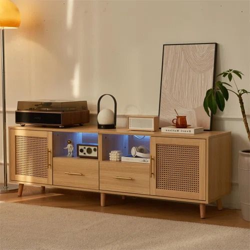 a living room with a tv, speakers and a plant on the sideboard in front of it