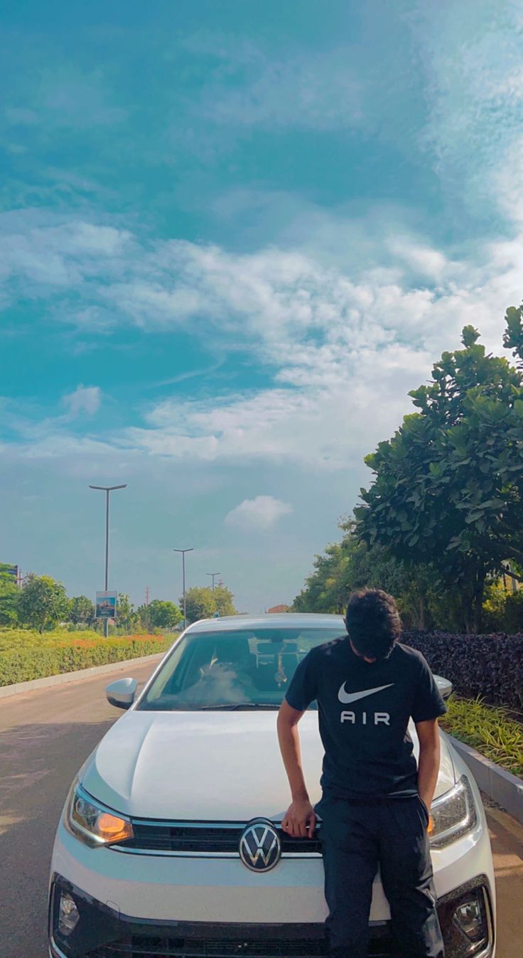 a man leaning on the hood of a white car