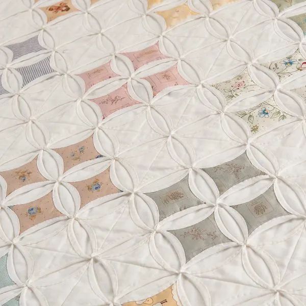 a close up view of a quilt made with white fabric and various colored squares on it