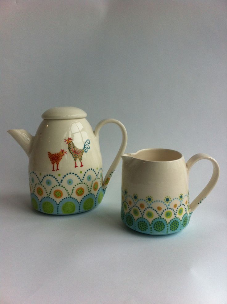 two teapots with designs on them sitting next to each other in front of a white background