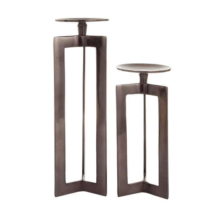 two metal candlesticks sitting next to each other