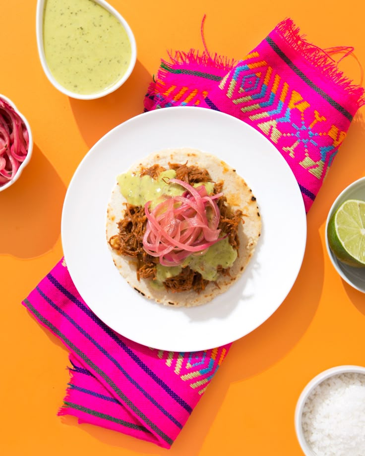 a taco on a plate next to bowls of salsa and guacamole