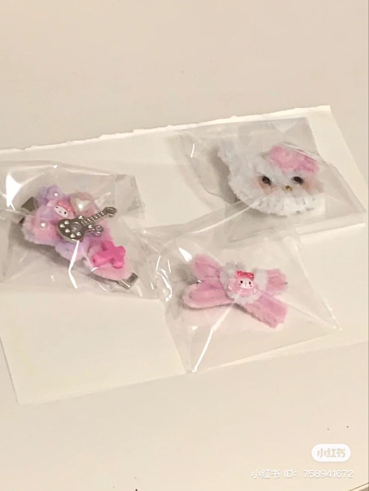 two small hair clips in plastic bags on top of a white table with pink flowers