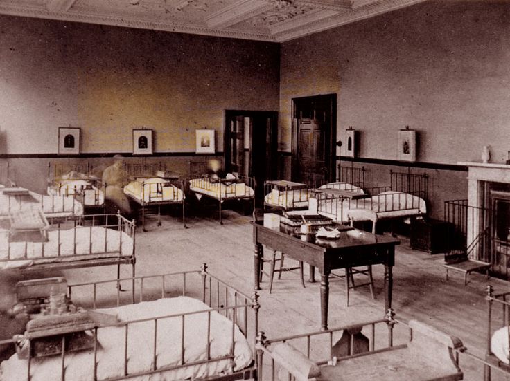 an old photo of a hospital room with beds and cots in the middle of it