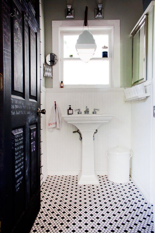 a bathroom with black and white tile flooring next to a sink, toilet and window