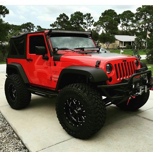 a red jeep parked on top of a driveway