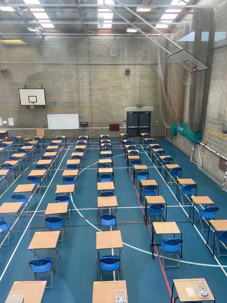 an indoor basketball court with rows of tables and chairs on the floor, all lined up