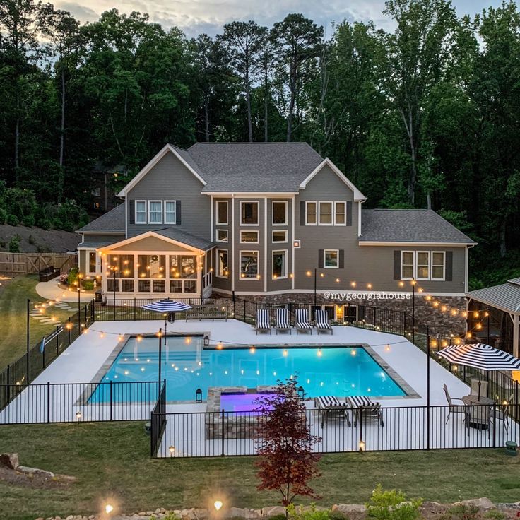 an aerial view of a house with a swimming pool and patio area at night time