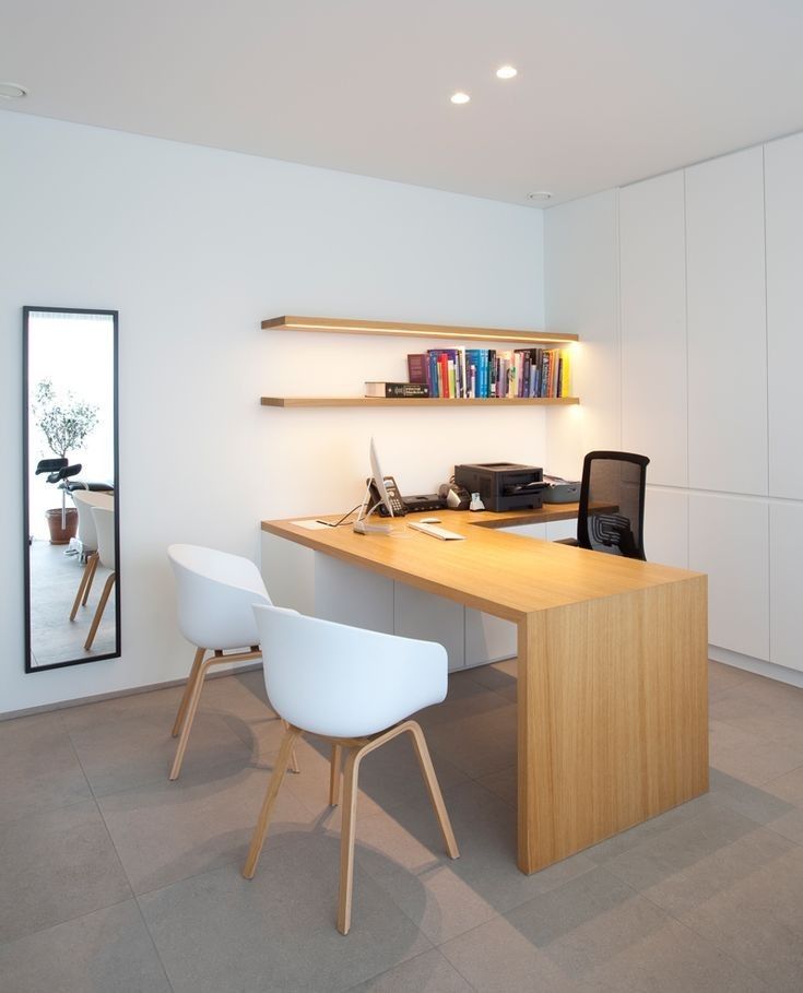 a desk with two chairs and a computer on it in a room that has white walls