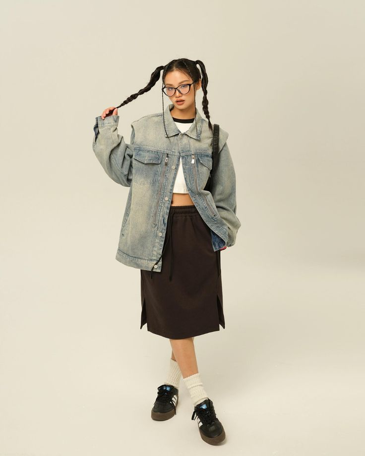 a young woman wearing glasses and a jean jacket is standing in front of a white background