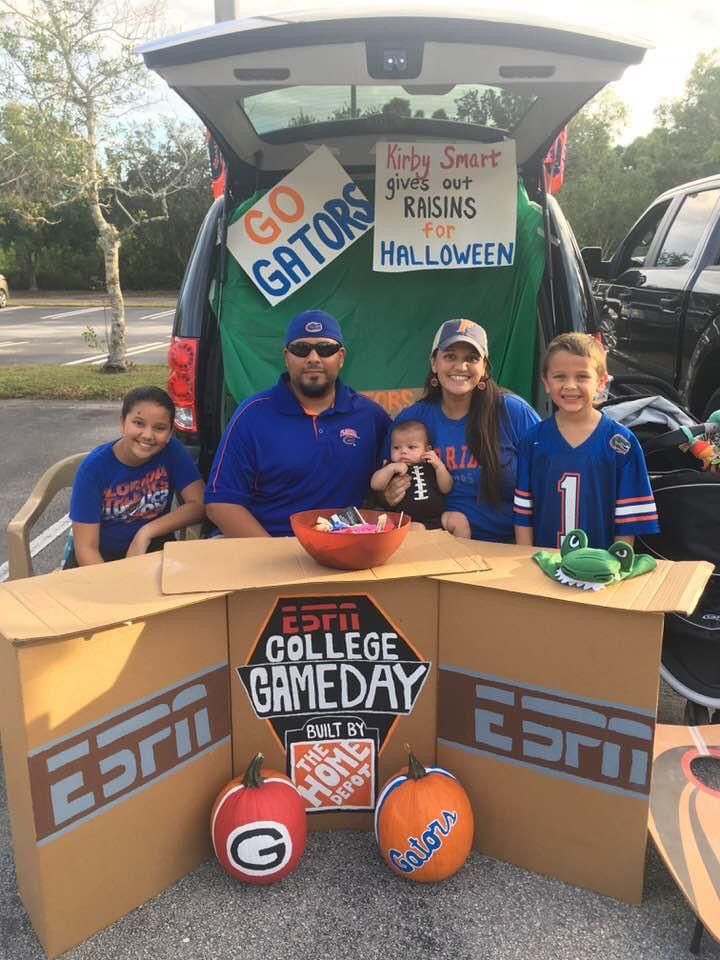 some kids and an adult are posing in front of a cardboard gameday truck with pumpkins