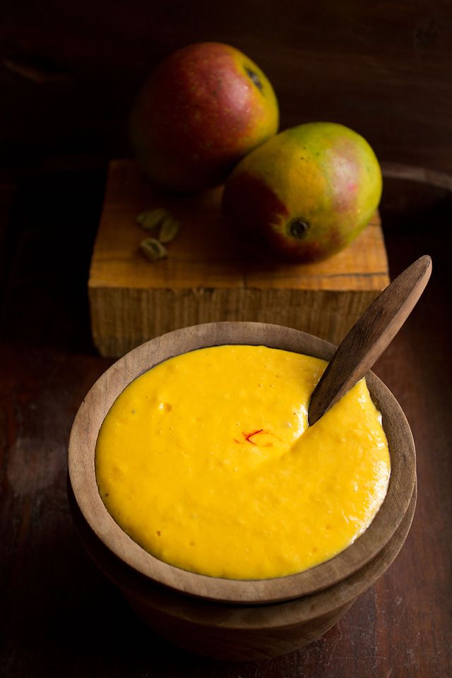 a wooden bowl filled with yellow liquid next to two apples