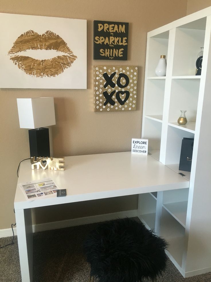 a white desk with some pictures on the wall behind it and a black furry rug