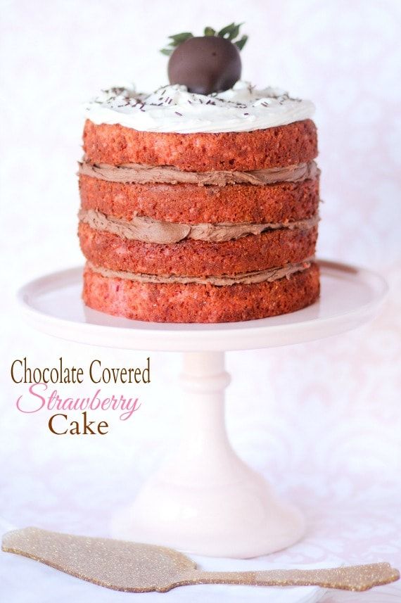 a chocolate covered strawberry cake on a white pedestal