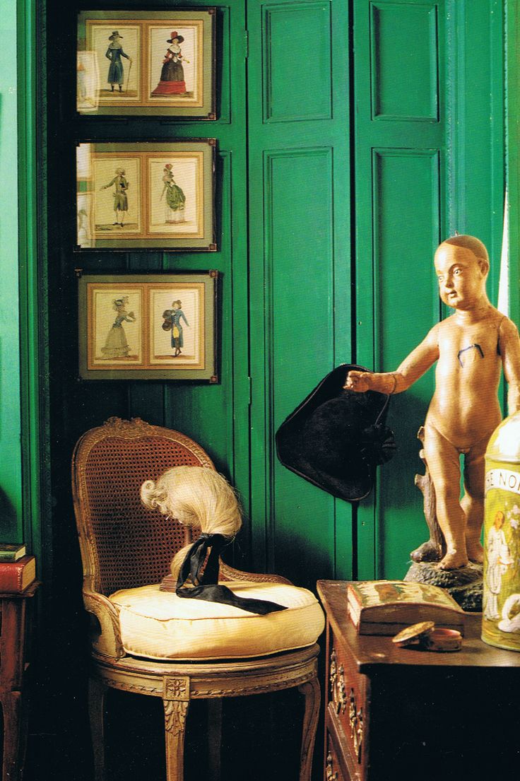 a room with green walls and pictures on the wall, including a statue of a boy holding a hat