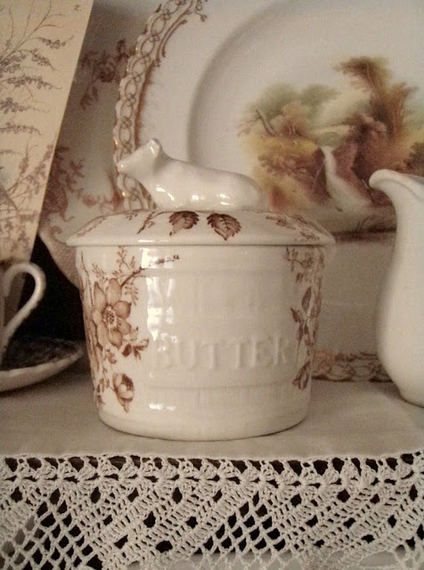 an old china cabinet with dishes and cups on it's shelf, along with lace doily