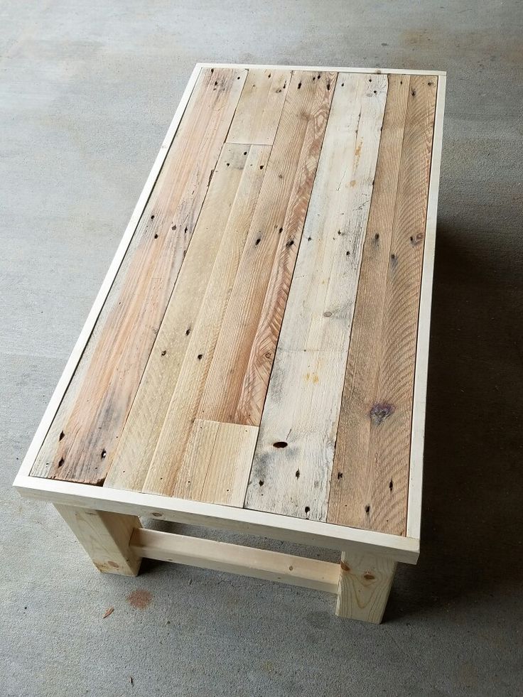 a table made out of wooden planks on concrete floor with no one around it