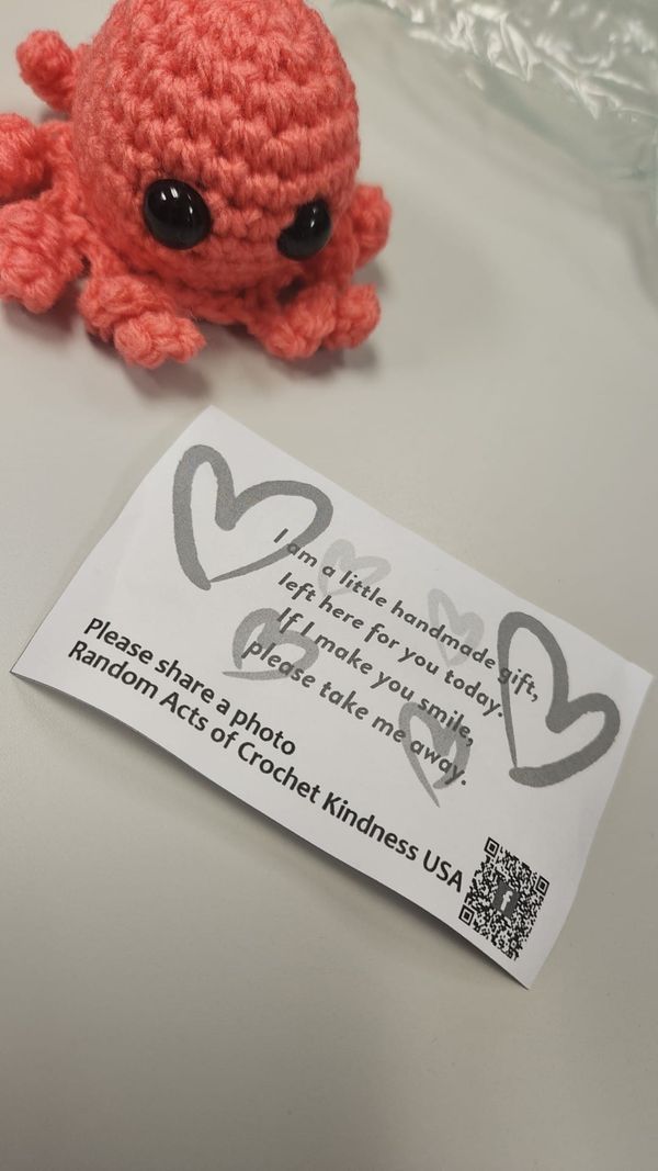 an orange crocheted octopus sitting on top of a table next to a card