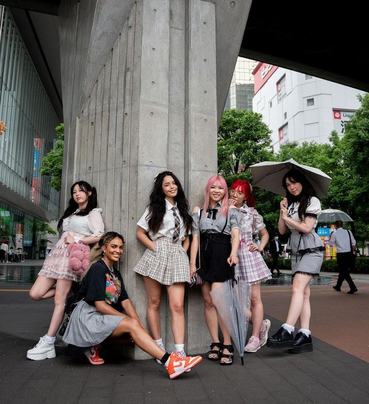 four girls are posing in front of a tall column