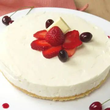 a cheesecake with strawberries and cherries on the top is ready to be eaten