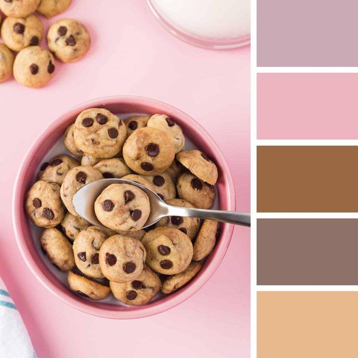 a pink bowl filled with chocolate chip cookies next to a cup of milk and spoon