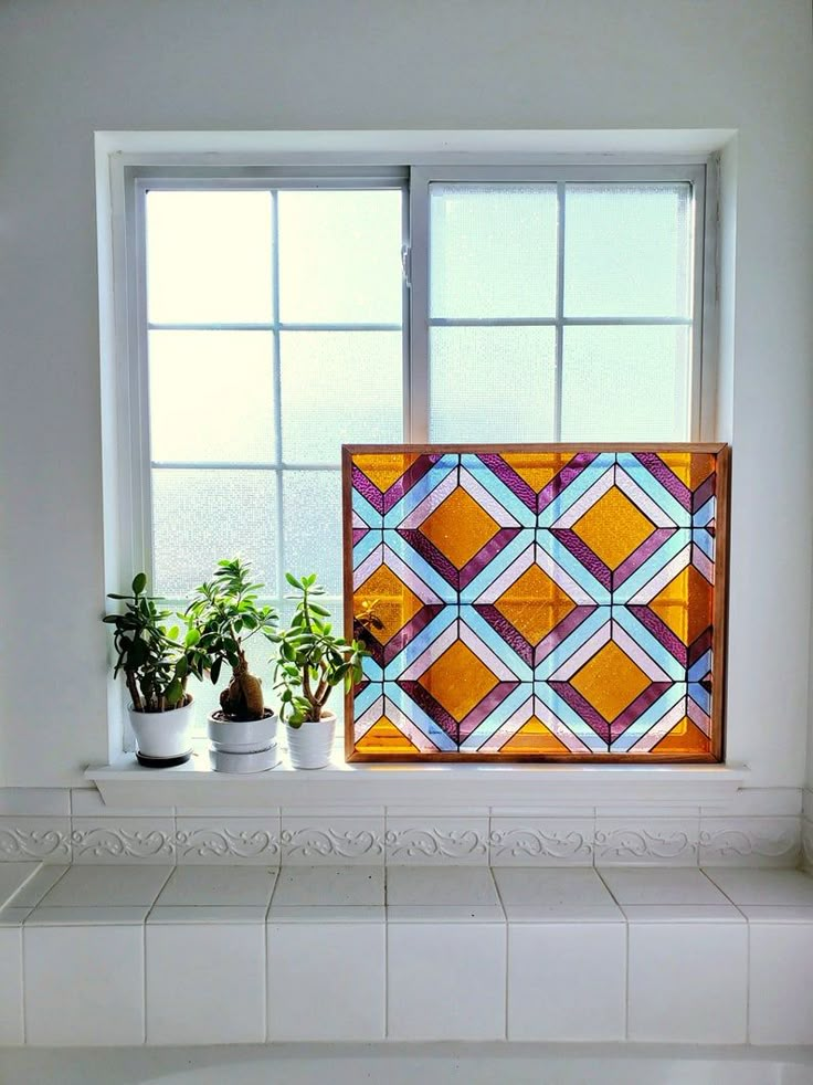 a bathroom window with potted plants on the ledge next to it and a tiled wall