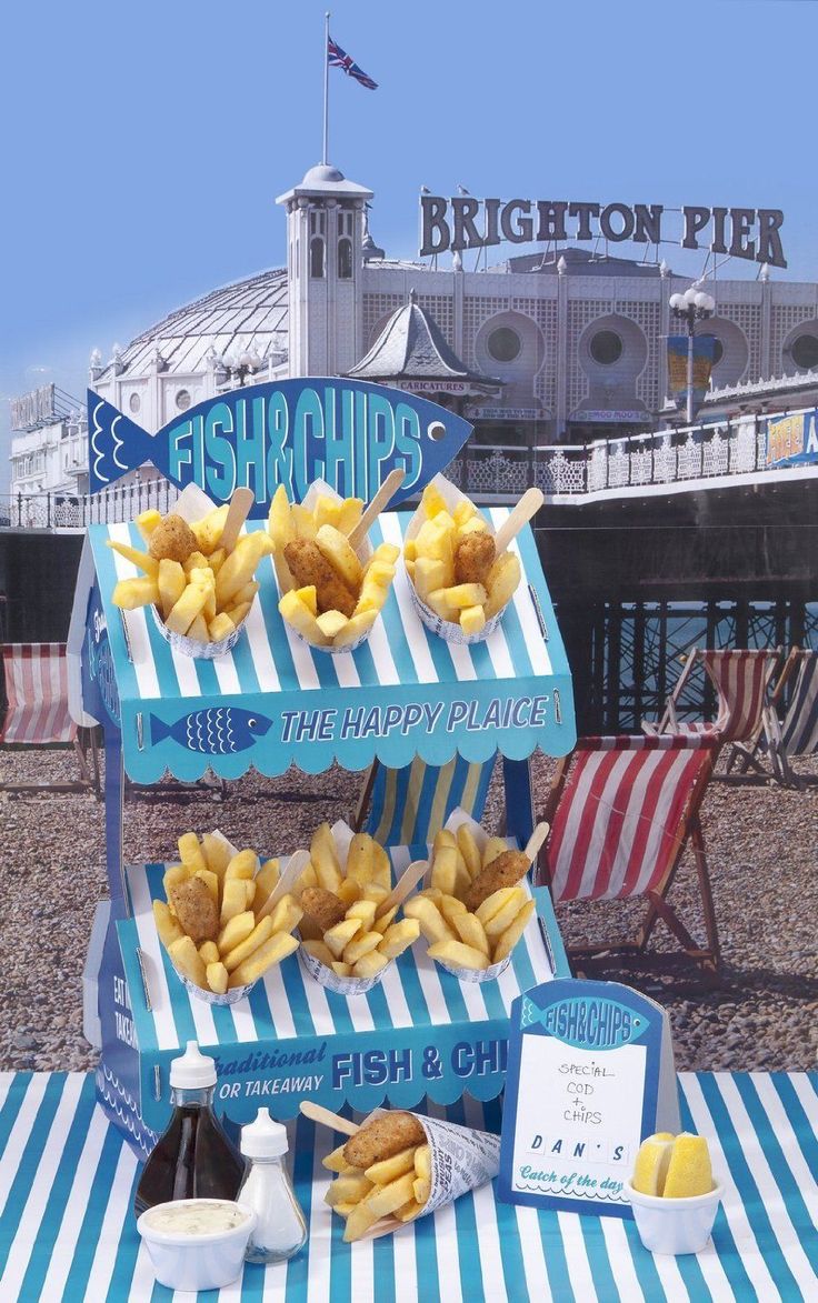 some food is sitting on top of a blue and white striped table cloth at the beach