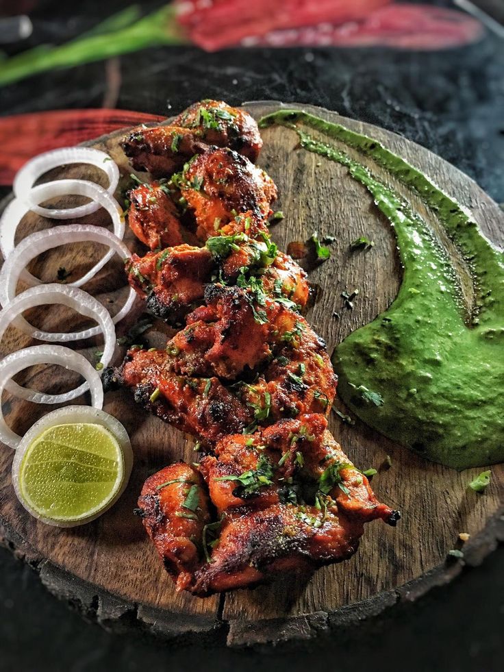 chicken skewers with guacamole and onion rings on a wooden board