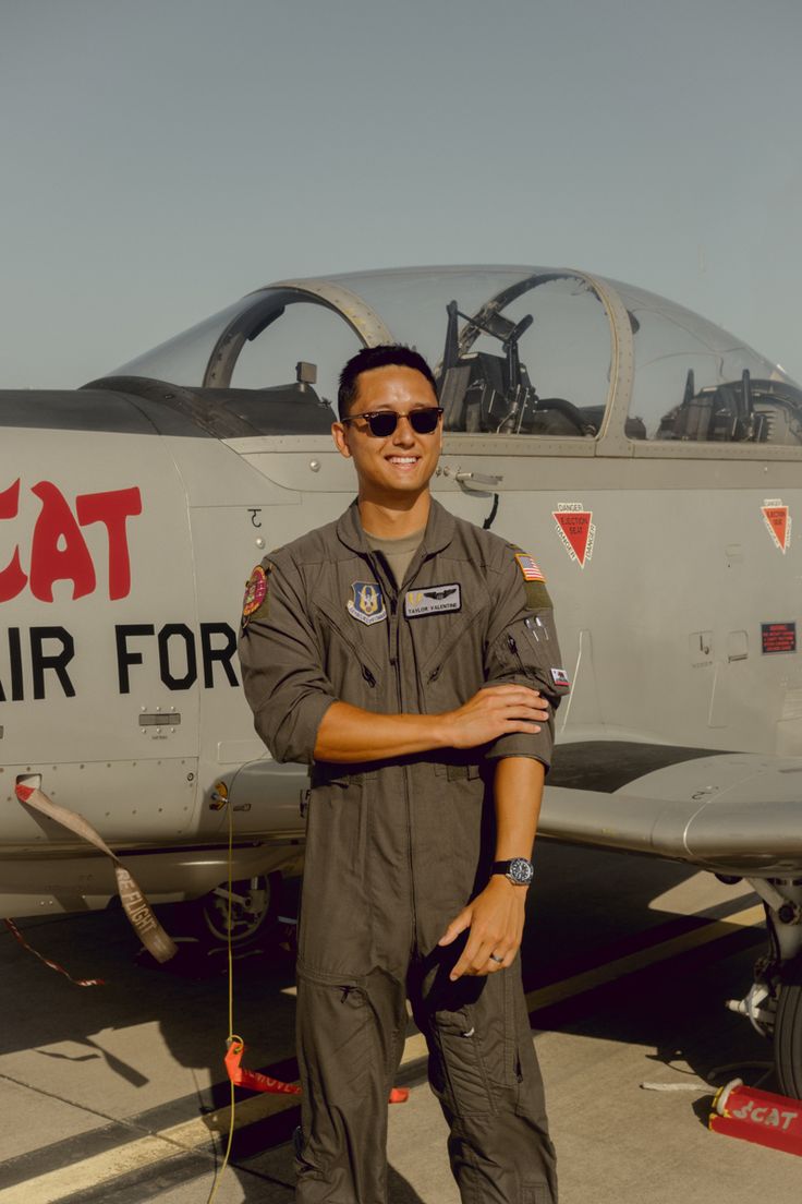 a man standing in front of an air force plane with his arms crossed and smiling at the camera