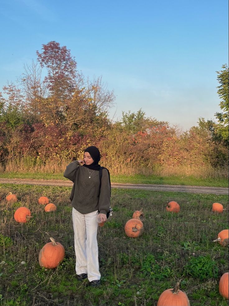 a woman standing in a field full of pumpkins