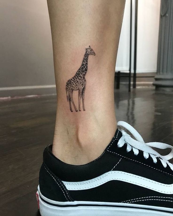 a small giraffe tattoo on the leg of a woman's lower body