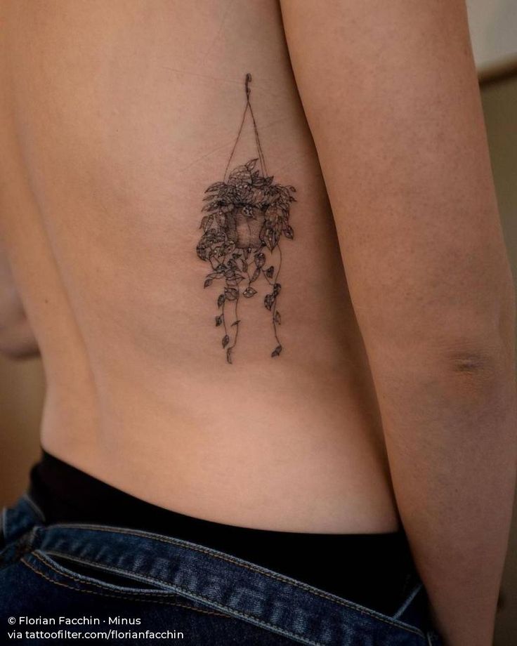 a woman's lower back tattoo with flowers and leaves on the side, hanging from a string