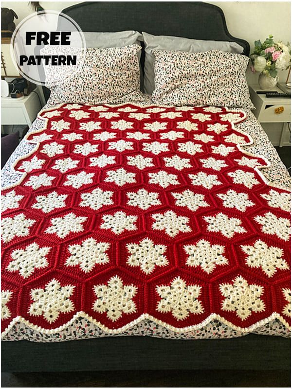 a red and white crocheted blanket sitting on top of a bed next to pillows