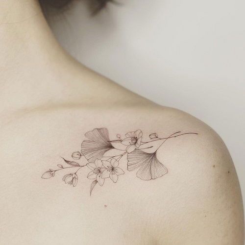 a woman's back with a flower tattoo on her left shoulder and the upper half of her body