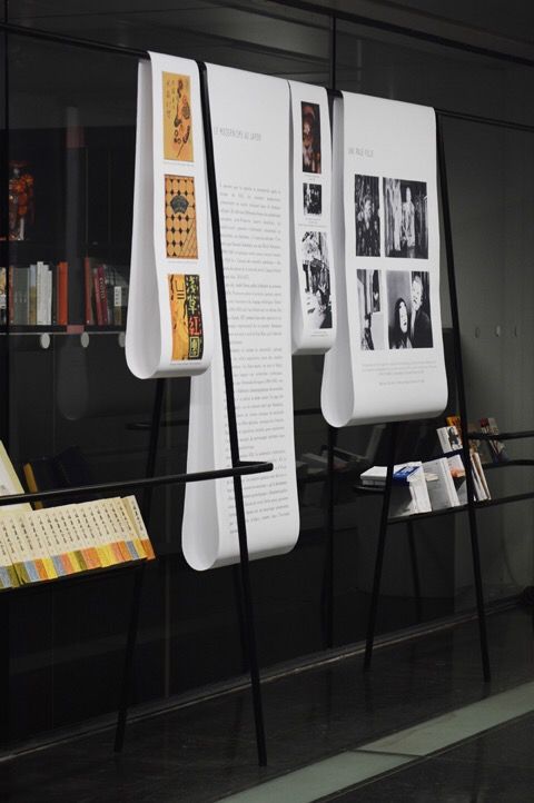 two white boards with pictures on them in front of a glass wall and bookshelf