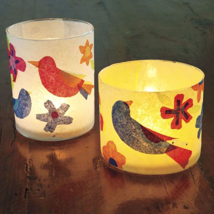 two candles sitting on top of a wooden table next to each other with birds painted on them