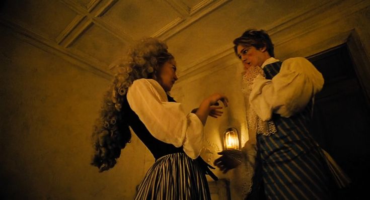 two women dressed in period clothing standing next to each other and one holding a lantern